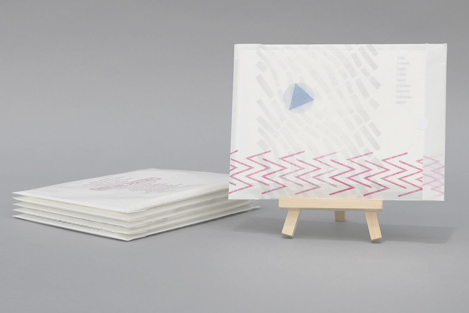 A stack of paper next to a single letter on a small wooden easel